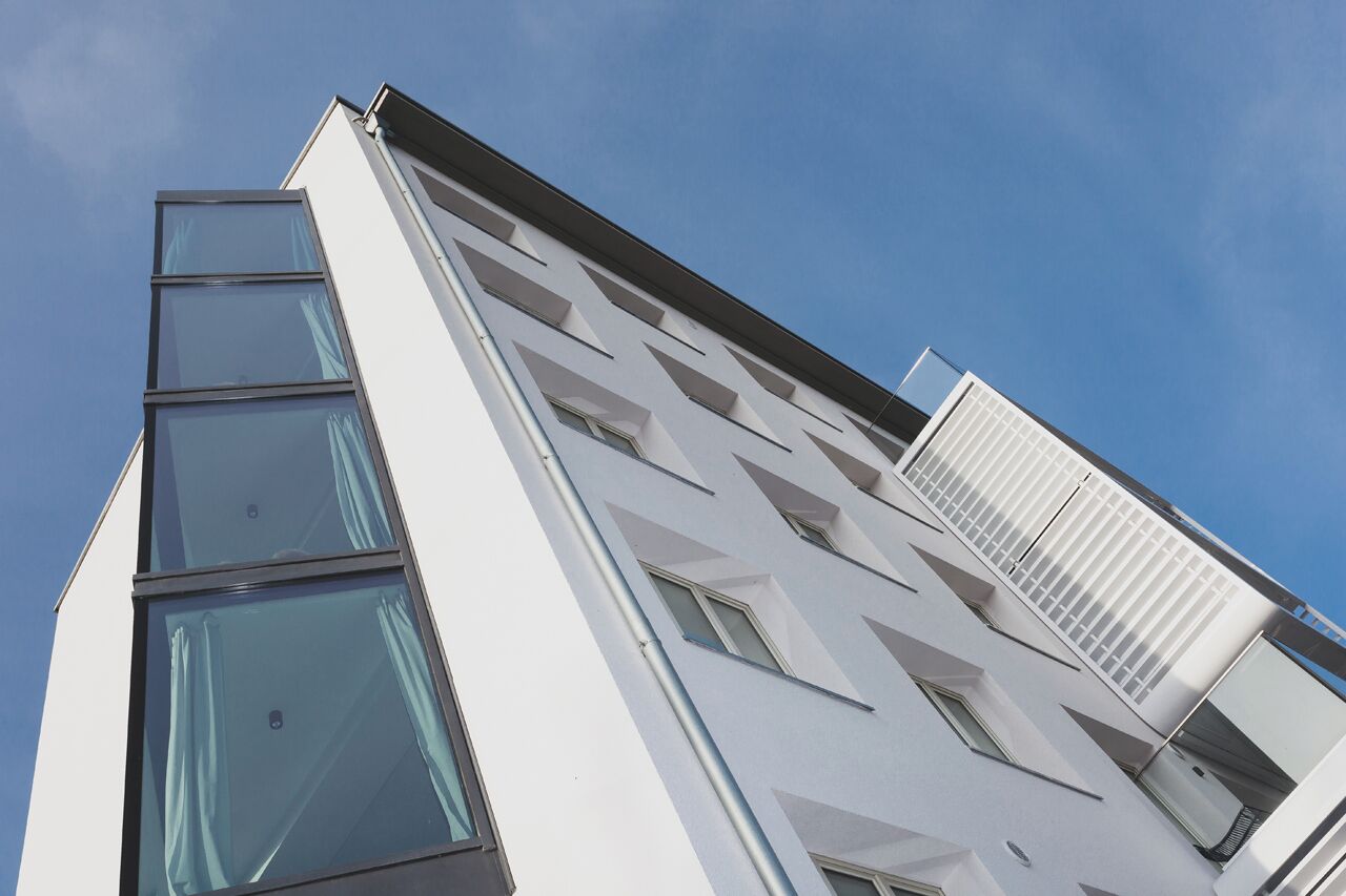 Ein modernes Gebäude mit heller Fassade und zahlreichen Fenstern.