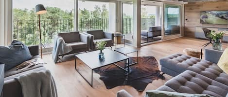 Ein großzügiger Wohnbereich mit einem großen Fenster, einem Sofa, einem Couchtisch und einem Kamin.