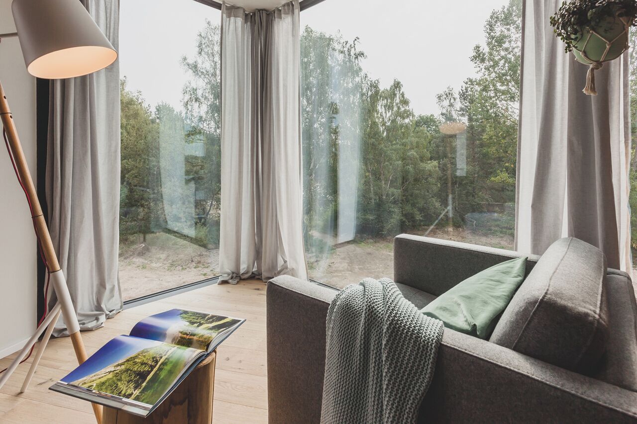 Ein modernes Wohnzimmer mit einem grauen Sofa, einer Lampe und einer Zeitschrift auf einem kleinen Tisch.