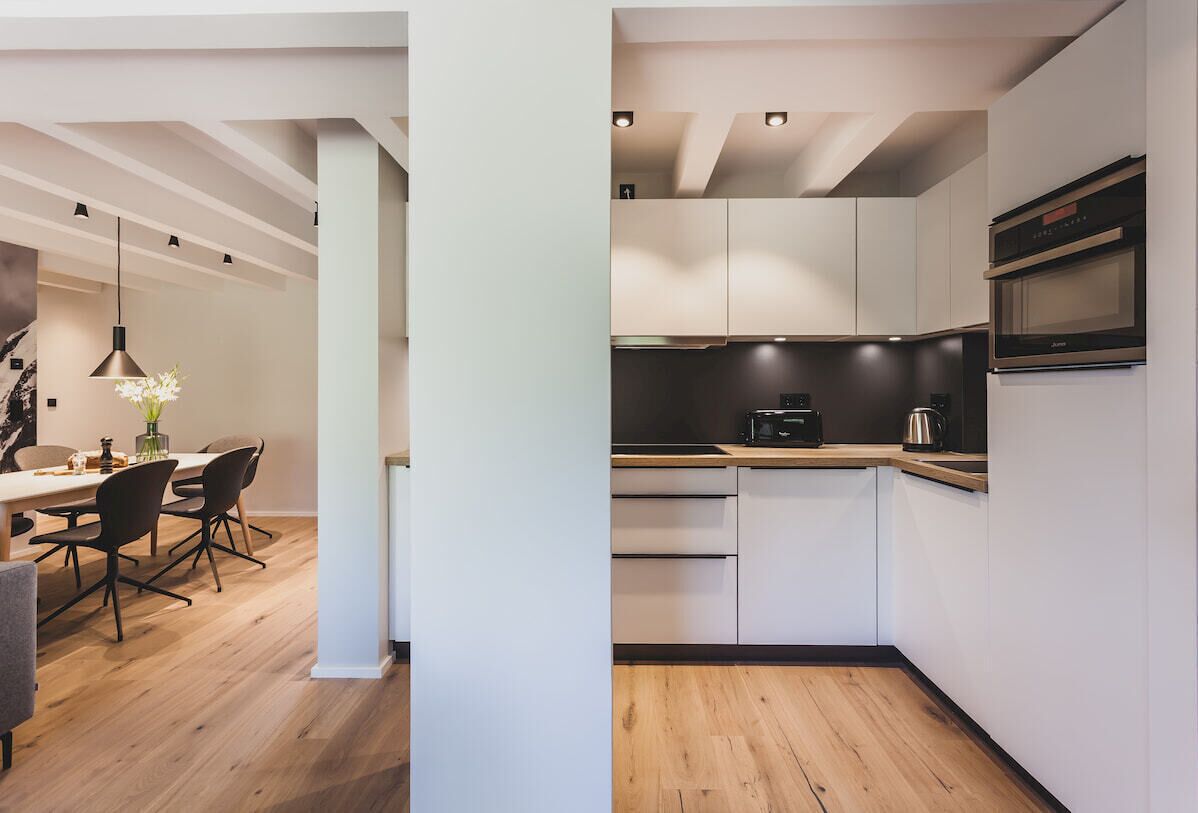 A modern kitchen with white cabinets, a built-in microwave, and a wooden countertop.