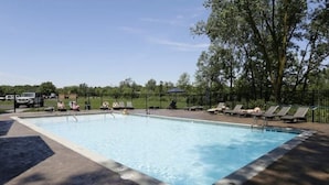A rectangular swimming pool with a tiled edge, surrounded by a paved deck. There are lounge chairs and umbrellas along the poolside. - 3 bedroom, 2 bath apartment. In Castle! With pool! Close to GR and lakeshore (Grandville)