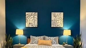 A bedroom with a bed, two wall-mounted lamps, and two wall art pieces. - 3 bedroom, 2 bath apartment. In Castle! With pool! Close to GR and lakeshore (Grandville)