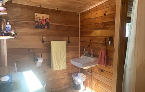A wooden cabin bathroom with a sink, two towels, a toilet, and a painting on the wall. - Quiet cabin on Center Pond. (Lincoln)