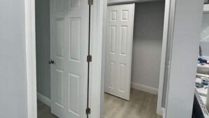 A hallway with white doors and a wooden floor. - 5 Min Walk-Beach, Surfing, Prime Location, Wi-Fi (West Palm Beach)