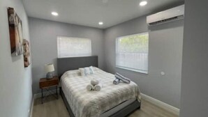 A modern bedroom with a bed, bedside table, and a window. - 5 Min Walk-Beach, Surfing, Prime Location, Wi-Fi (West Palm Beach)
