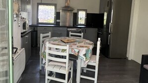 A compact kitchen with a dining area, a built-in oven, a refrigerator, and a TV mounted on the wall. - Barcarès, ile des Pêcheurs, Mas Bord de Marina (Le Barcarès)