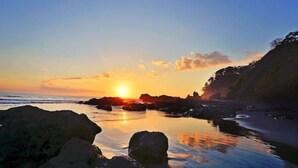A coastal sunset scene with rocky formations and calm waters. - Breathtaking Ocean View Condo (Jaco)