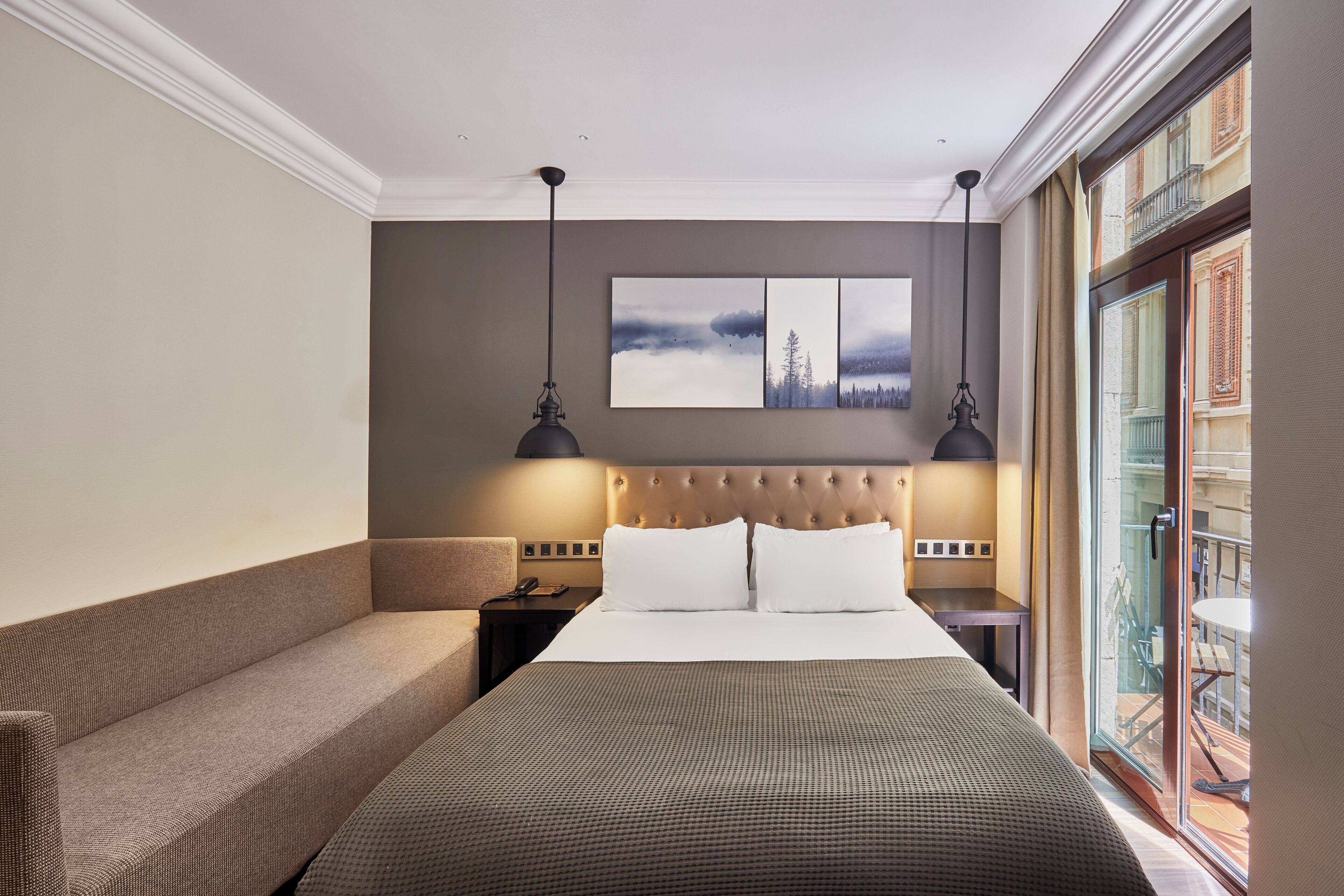 Une chambre d’hôtel avec un grand lit, un canapé, une table de chevet et un tableau au mur.