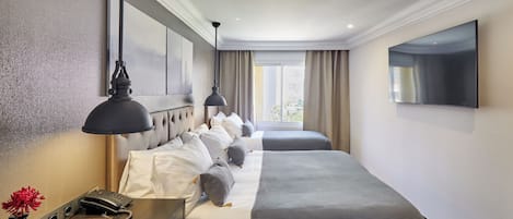 Habitación de hotel con una cama grande, mesitas de noche, un escritorio con teléfono y un televisor de pantalla plana montado en la pared.
