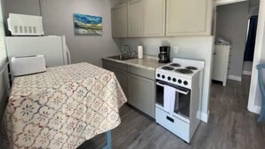 A compact kitchen with a bed, a stove, and a refrigerator. - BBQ Grill, 5 Min Walk-Beach, Surf, Snorkel (West Palm Beach)