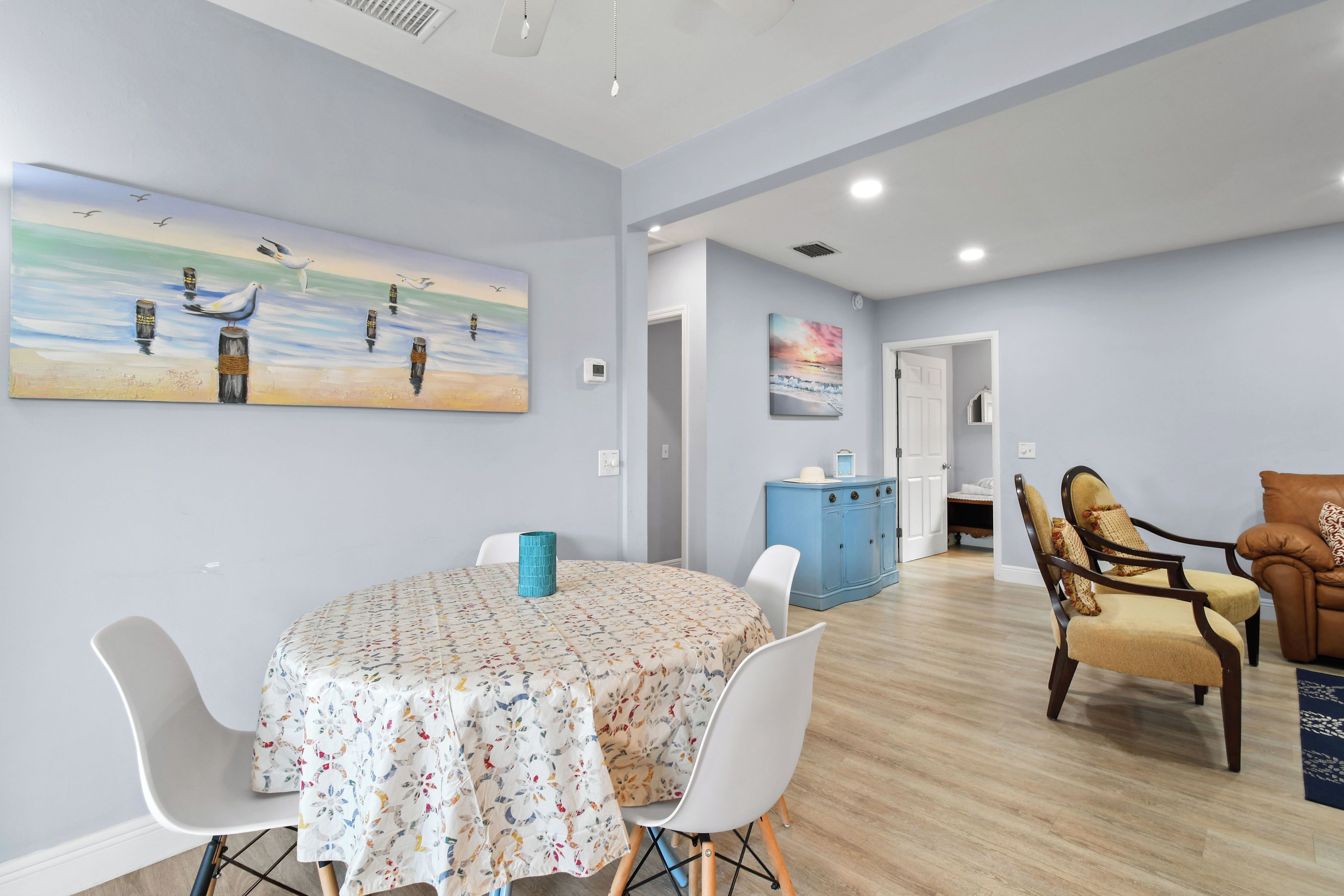 A dining area with a round table, white chairs, and a blue cabinet.