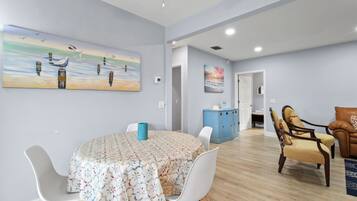 A dining area with a round table, white chairs, and a blue cabinet.