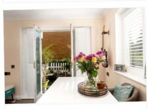 Enjoy a bright and airy space with a large window, a central table, and a vase of flowers.