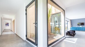 Un interior moderno con una puerta de cristal que da a un jardín, un sofá azul y un diseño minimalista.