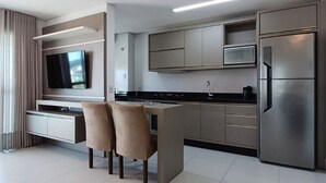 A modern kitchen with a built-in island, stainless steel appliances, and a flat-screen TV. - Ap Praia de Ouro - Venice Home Club (Picarras)