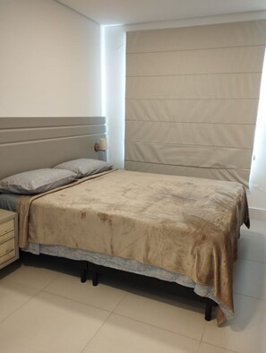 A bedroom with a bed, nightstand, and a wall-mounted light. - Ap Praia de Ouro - Venice Home Club (Picarras)