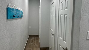 A hallway with a textured wall, a blue artwork, and a white door. - Beach Retreat Fun In The Sun Cozy Ambiance (Galveston)