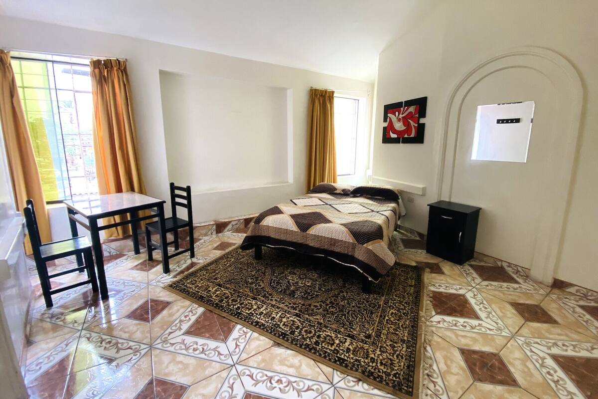 A bedroom with a bed, a desk, and a chair.
