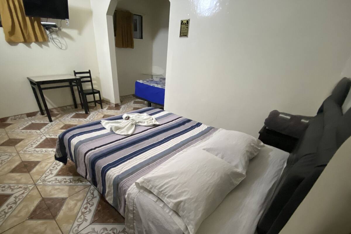 A bedroom with a bed, a desk, and a chair.