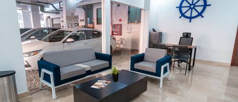 Um lobby moderno com área de estar, mesa de centro e um volante decorativo fixado na parede.