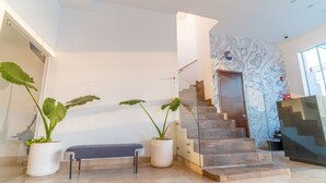 Un intérieur moderne avec un escalier, des plantes en pot et un banc.