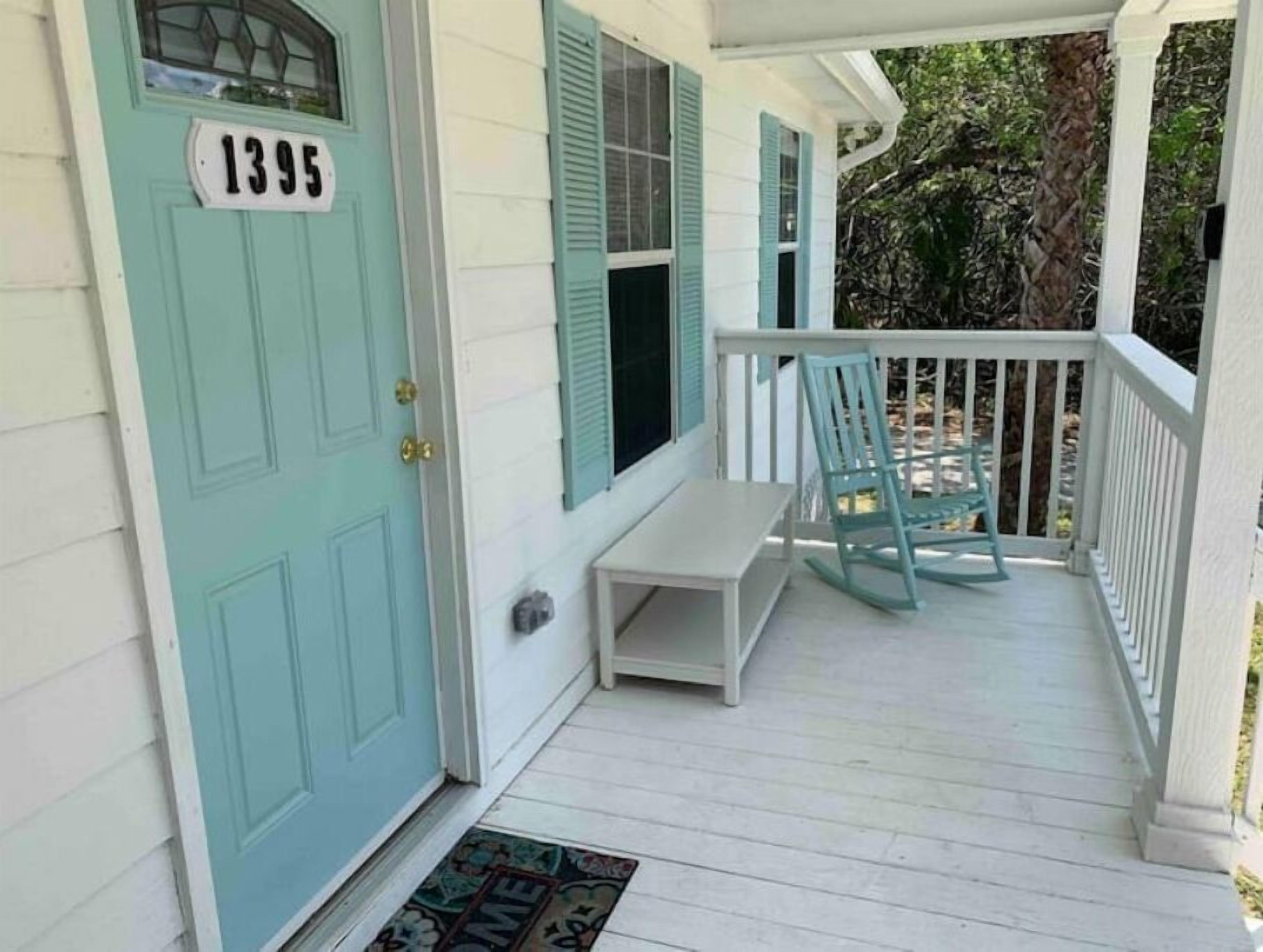 A porch with a light blue door, a white bench, and a rocking chair.