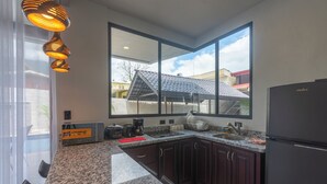 Eine moderne Küche mit Granitarbeitsplatten, dunklen Holzschränken, einem schwarzen Kühlschrank und einem großen Fenster mit Blick auf ein Haus.