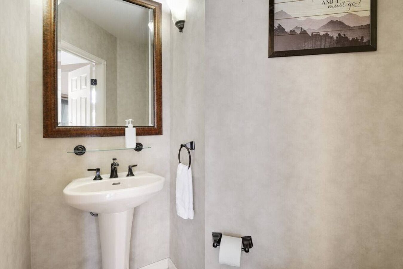 A bathroom with a white sink, a mirror with a wooden frame, and a towel rack.