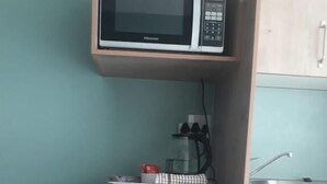 A compact kitchenette with a microwave, a small refrigerator, a water dispenser, and a sink.