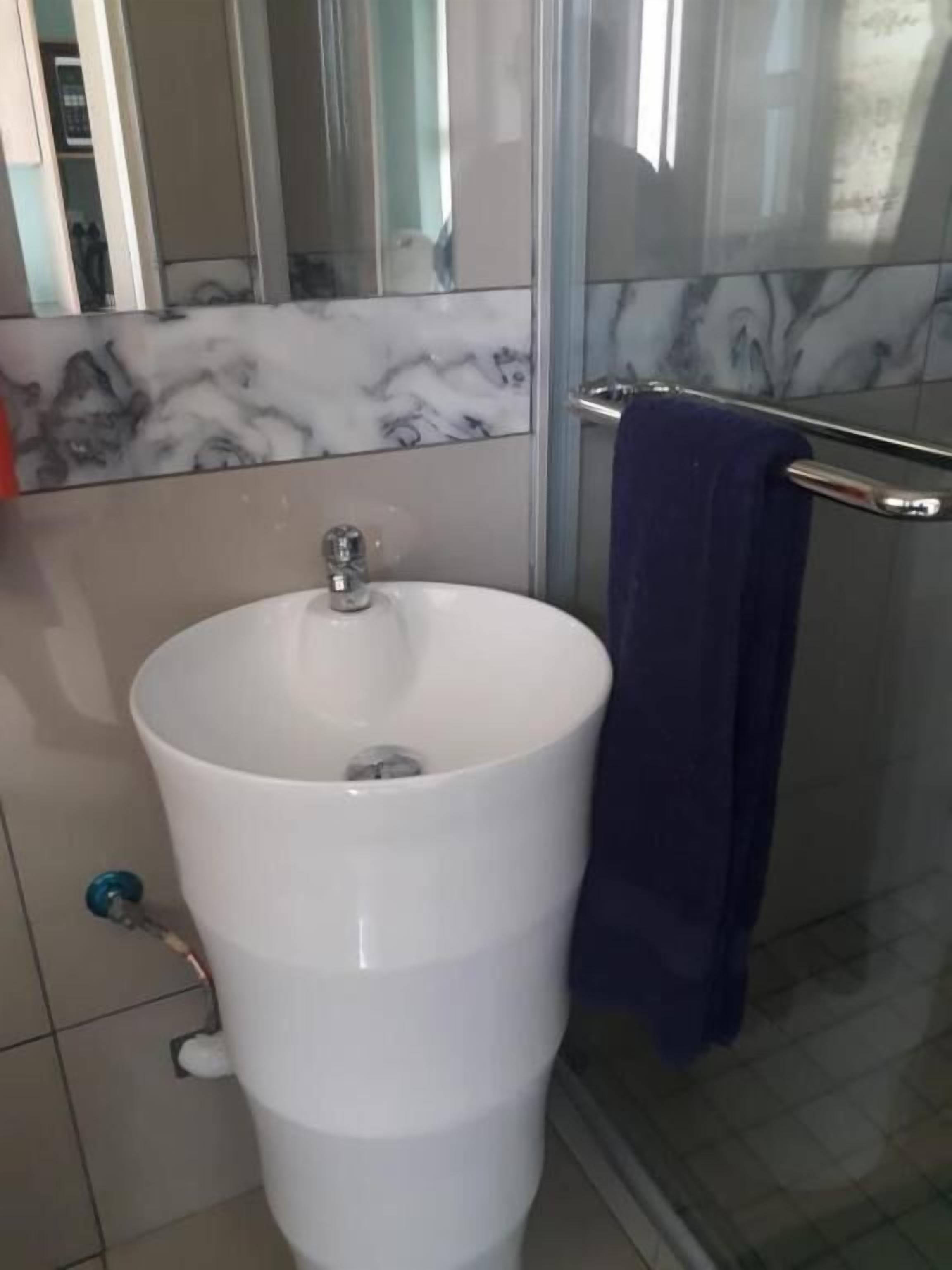 Un bagno con lavandino bianco, uno specchio e zona doccia.