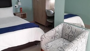 A hotel room with two beds, a wardrobe, a desk, and a chair.