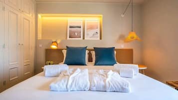 A hotel room with a large bed, two pillows, a bedside table, a lamp, and a wall-mounted picture.