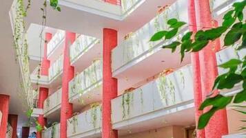 A multi-level atrium with hanging plants, red pillars, and a glass ceiling.