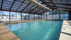 An indoor swimming pool with a glass ceiling, clear pool water, and a view of the outside. - Updated condo in Branson w/ golf course view, sleeps 1-4 (Branson)