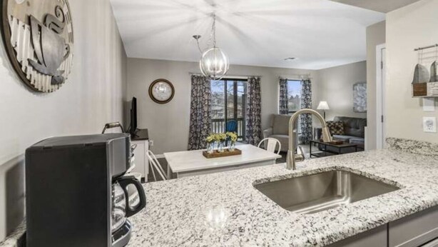 A modern kitchen with granite countertops, a coffee maker, and a dining area with a chandelier. - Updated condo in Branson w/ golf course view, sleeps 1-4 (Branson)
