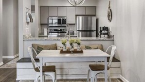 A modern kitchen with stainless steel appliances, a dining area with a white table and chairs, and a pendant light above the table. - Updated condo in Branson w/ golf course view, sleeps 1-4 (Branson)