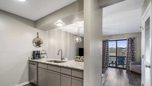A modern kitchen with a built-in dishwasher, a coffee maker, and a pendant light. - Updated condo in Branson w/ golf course view, sleeps 1-4 (Branson)