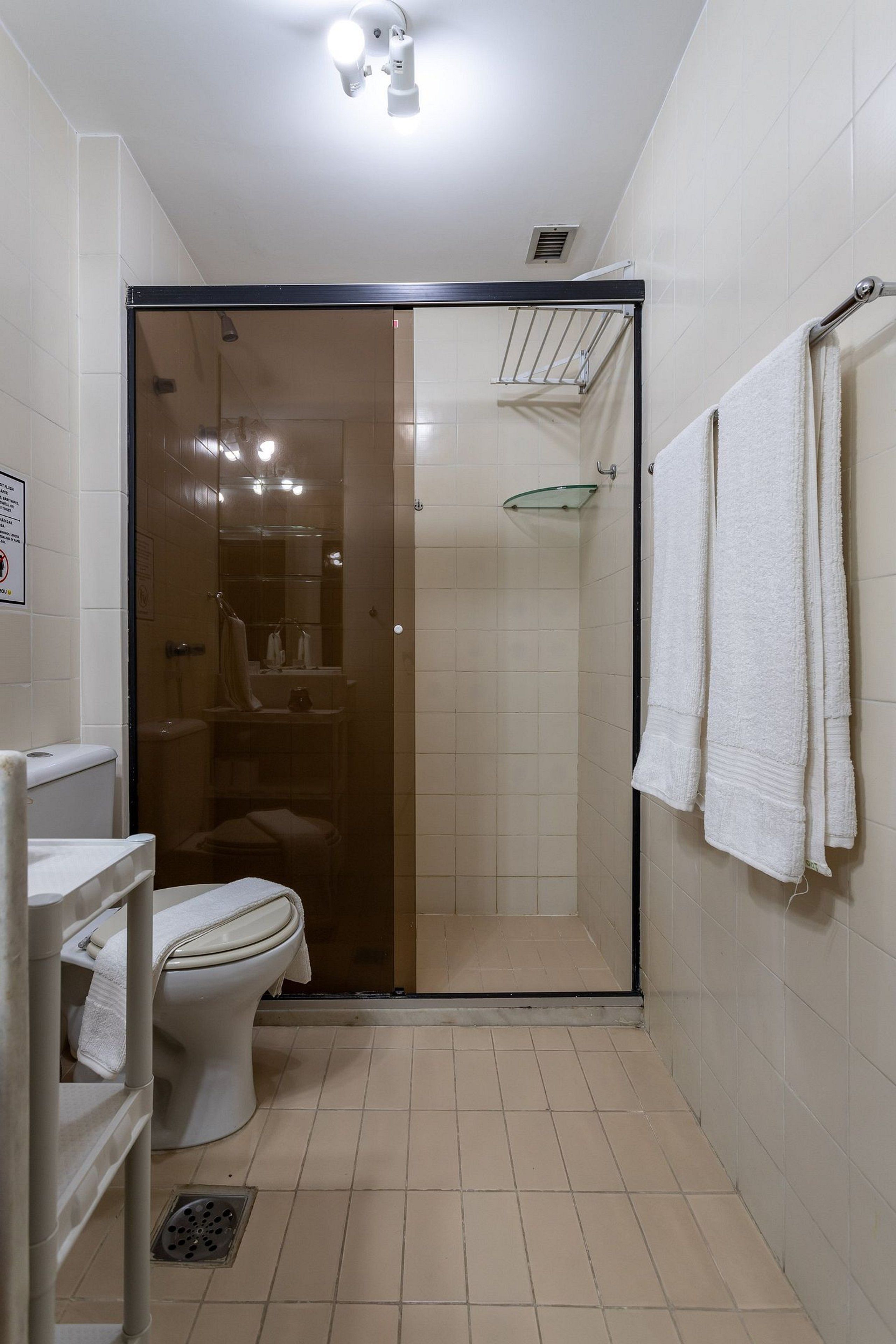 A small bathroom with a toilet, a glass shower enclosure, and a towel rack.