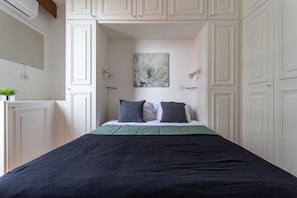A bedroom with a bed, a nightstand, a wall-mounted lamp, and a painting. - (1008) Apartamento com 1 Quarto e Vista para o Cristo (Rio de Janeiro)