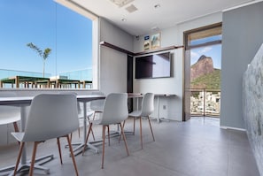 Un comedor moderno con un amplio ventanal, un televisor de pantalla plana en la pared y vistas a la montaña.