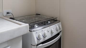 Cozinha compacta com fogão a gás, forno e exaustor.