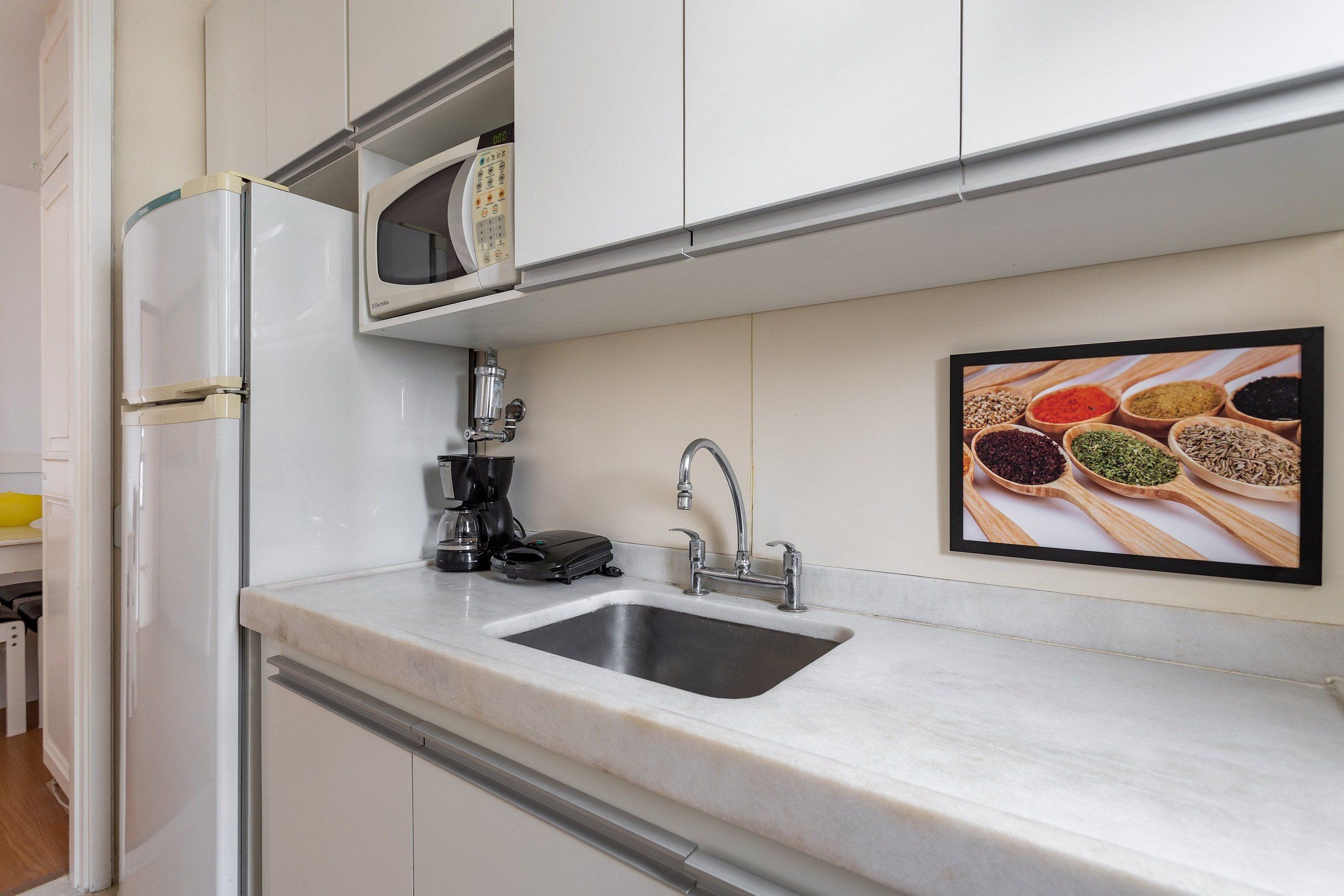 A kitchen with a built-in microwave, coffee maker, and sink.