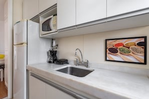 A kitchen with a built-in microwave, coffee maker, and sink. - (1008) Apartamento com 1 Quarto e Vista para o Cristo (Rio de Janeiro)