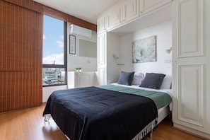 Relax in this stylish bedroom with a large bed, white cabinetry, and a city view.