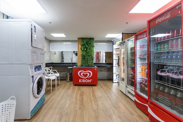 A laundry room with a washing machine, a Kibon branded counter, and a Coca-Cola refrigerator. - (1008) Apartamento com 1 Quarto e Vista para o Cristo (Rio de Janeiro)