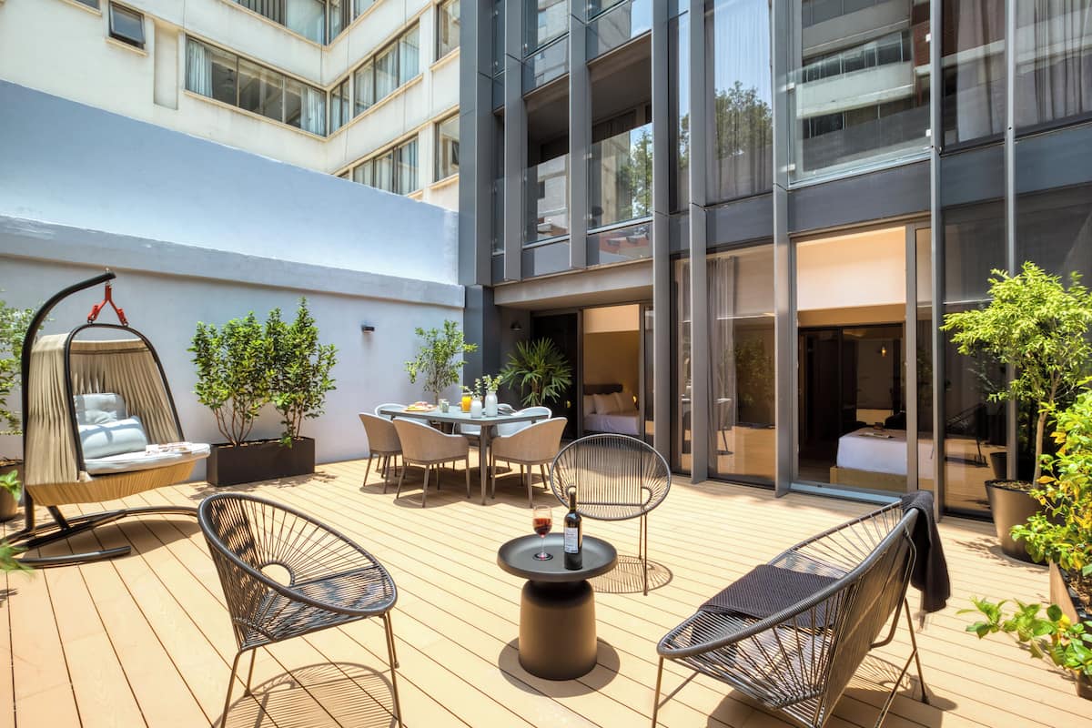 A modern outdoor patio with a dining table, chairs, and a hanging chair.