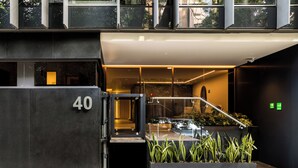 A modern building entrance with a glass door, a visible staircase, and a number '40' on the wall. - ULIV Parque Lincoln (Mexico City)