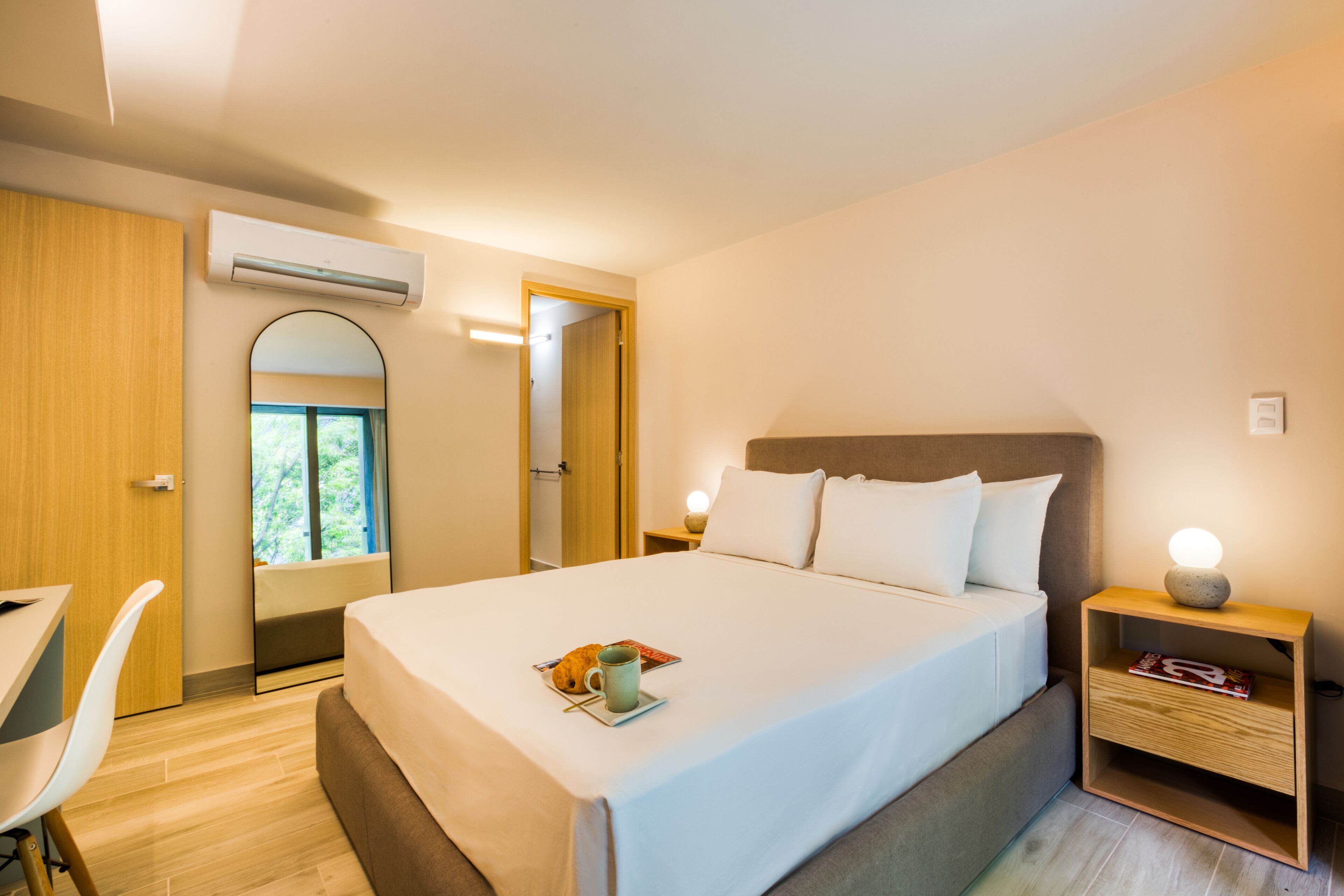 A modern hotel room with a neatly made bed, a desk, and a chair.