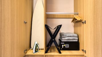 Un meuble de rangement compact doté d’une tringle pour suspendre les vêtements, d’une planche à repasser et d’une petite table à repasser.