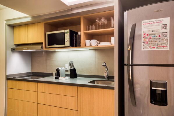 A modern kitchen with wooden cabinets, a stainless steel refrigerator, a microwave, and a coffee maker. - ULIV Parque Lincoln (Mexico City)